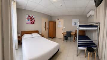 Een hotelkamer met een bed, een bureau, een stoel, een kledingkast en een stapelbed.