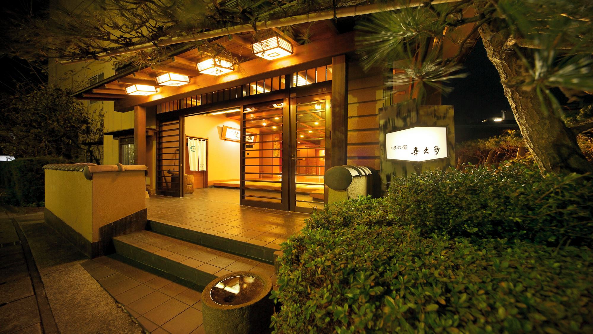 A traditional Japanese building with a wooden exterior, a tiled entrance, and a sign indicating a restaurant.