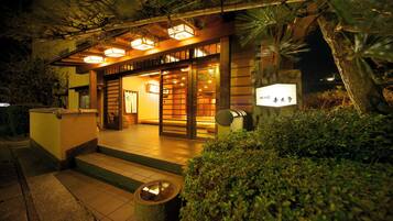 A traditional Japanese building with a wooden exterior, a tiled entrance, and a sign indicating a restaurant.