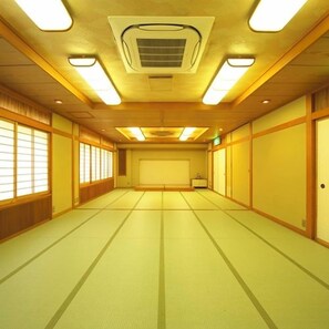 Een kamer met tatami vloeren, schuifdeuren en een plafond met inbouwverlichting.