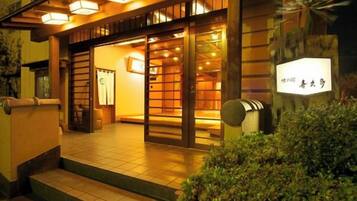 Un edificio de estilo japonés tradicional, con fachada de madera, entrada de tejas y un letrero con caracteres japoneses.