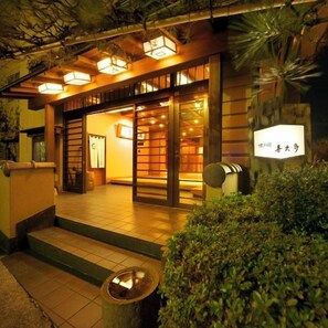 Un edificio de estilo japonés tradicional, con fachada de madera, entrada de tejas y un letrero con caracteres japoneses.