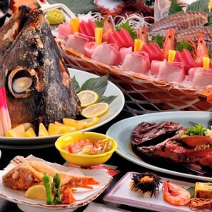 Verschiedene Fischgerichte, darunter gegrillter Fisch, Garnelen und Sashimi.