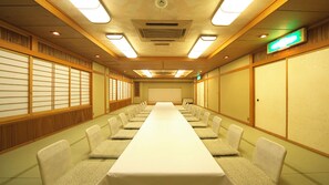 Une salle de conférence équipée d’une longue table, de chaises et d’un écran de projection.