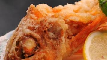 A piece of fried fish with a lemon wedge on a plate.