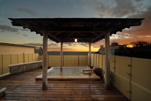 Un terrazza in legno con una pergola, affacciata su un corso d'acqua ed edifici.