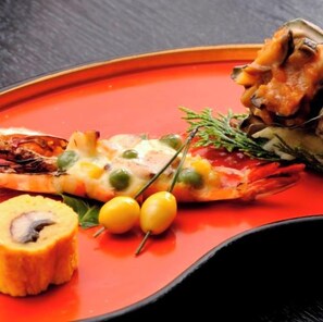 Un plato con un alimento a la parrilla, posiblemente pescado, acompañado de un objeto pequeño y redondo y dos bayas amarillas.