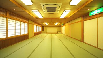 Una habitación tradicional japonesa con suelo de tatami, puertas correderas y un ventilador de techo.