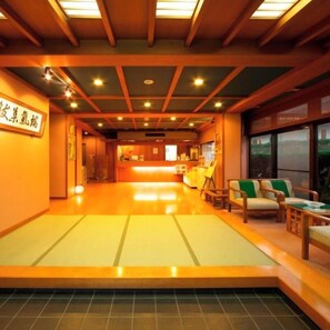 Een traditioneel Japans herberginterieur met tatami vloeren, houten meubels en een receptiebalie.