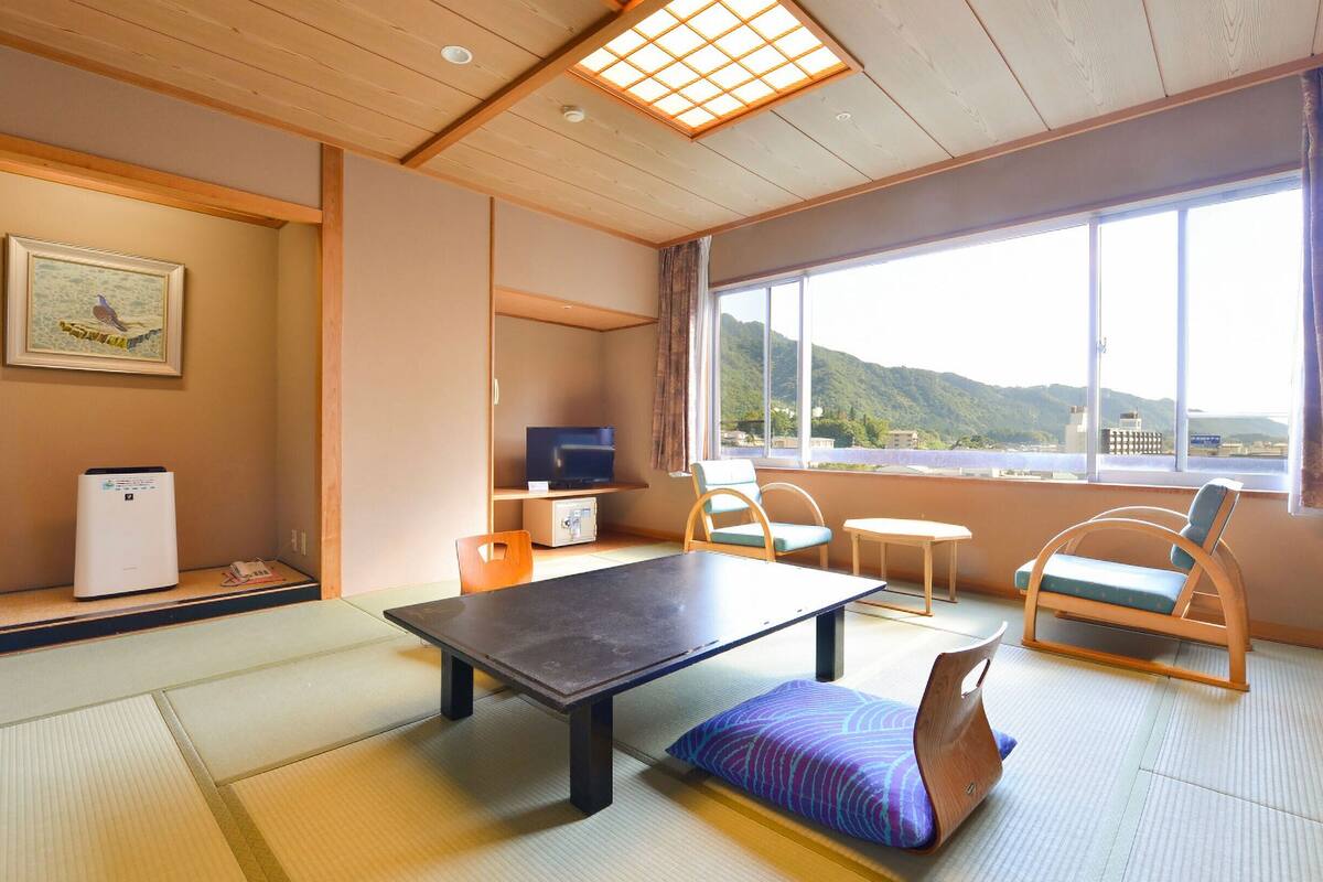 Ett traditionellt japanskt rum med tatamimattor på golvet, ett lågt bord och en tv.