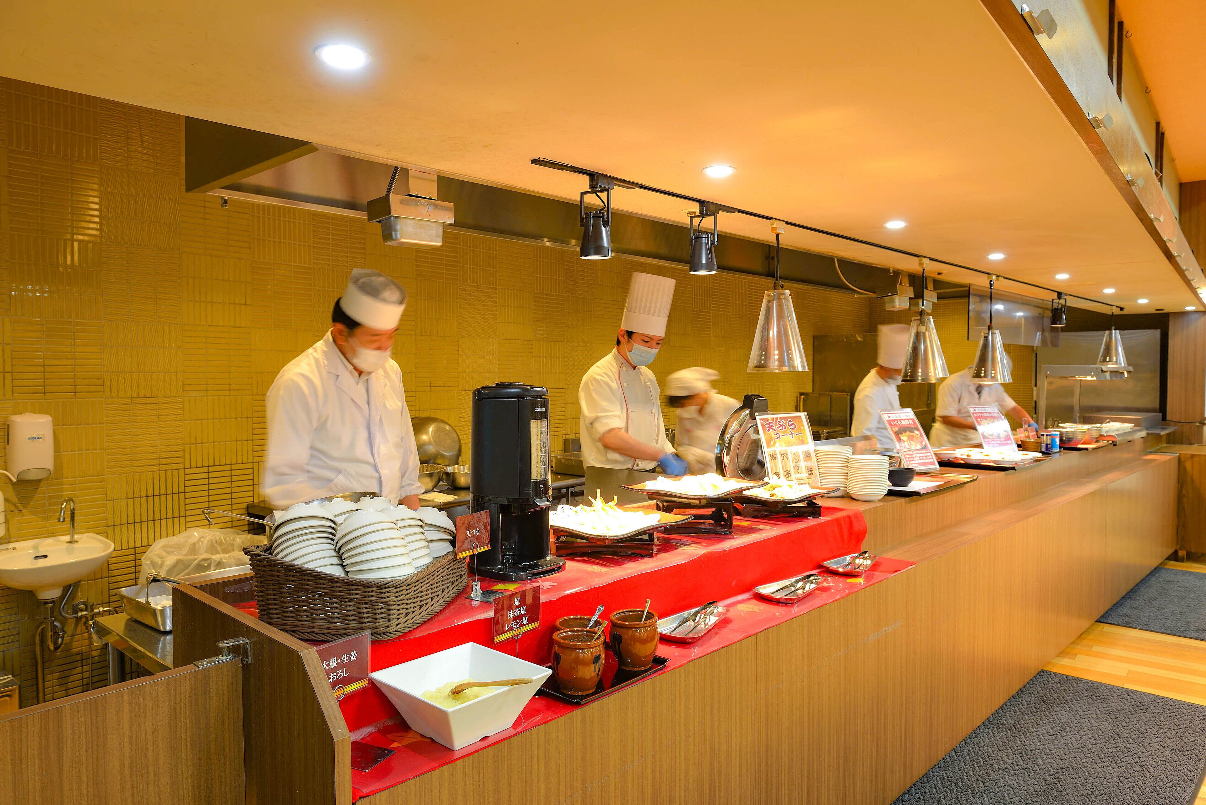 A buffet setup with multiple serving stations, a sink, and a counter with various food items and utensils.