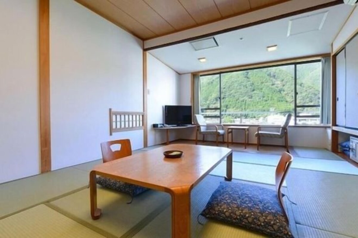 Una habitación japonesa tradicional con suelo de tatami, una mesa baja y un televisor.