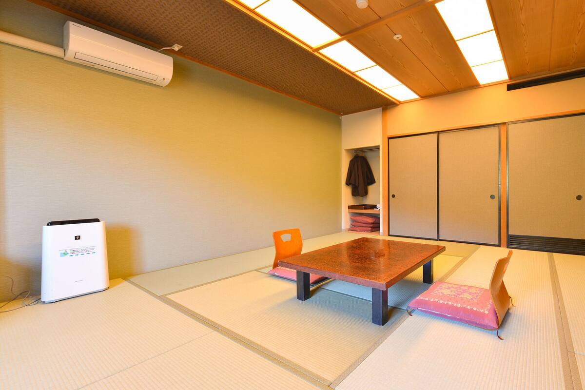 Ett traditionellt japanskt rum med tatamimattor på golvet, ett lågt bord och en skjutdörr.