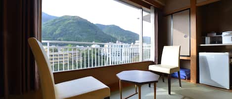 Una habitación con vista a las montañas, una pequeña mesa, dos sillas y un refrigerador.