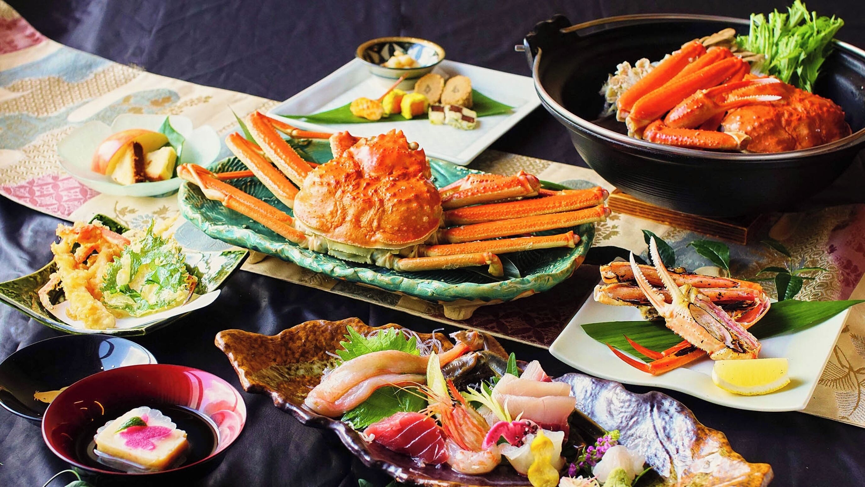 A variety of seafood dishes, including crab legs and sashimi, arranged on a table.