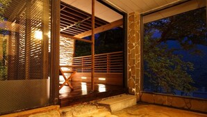 A traditional Japanese onsen with a wooden deck and stone steps leading to a hot spring.