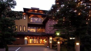 A multi-story hotel with a traditional architectural style, featuring a prominent entrance and illuminated exterior lights.