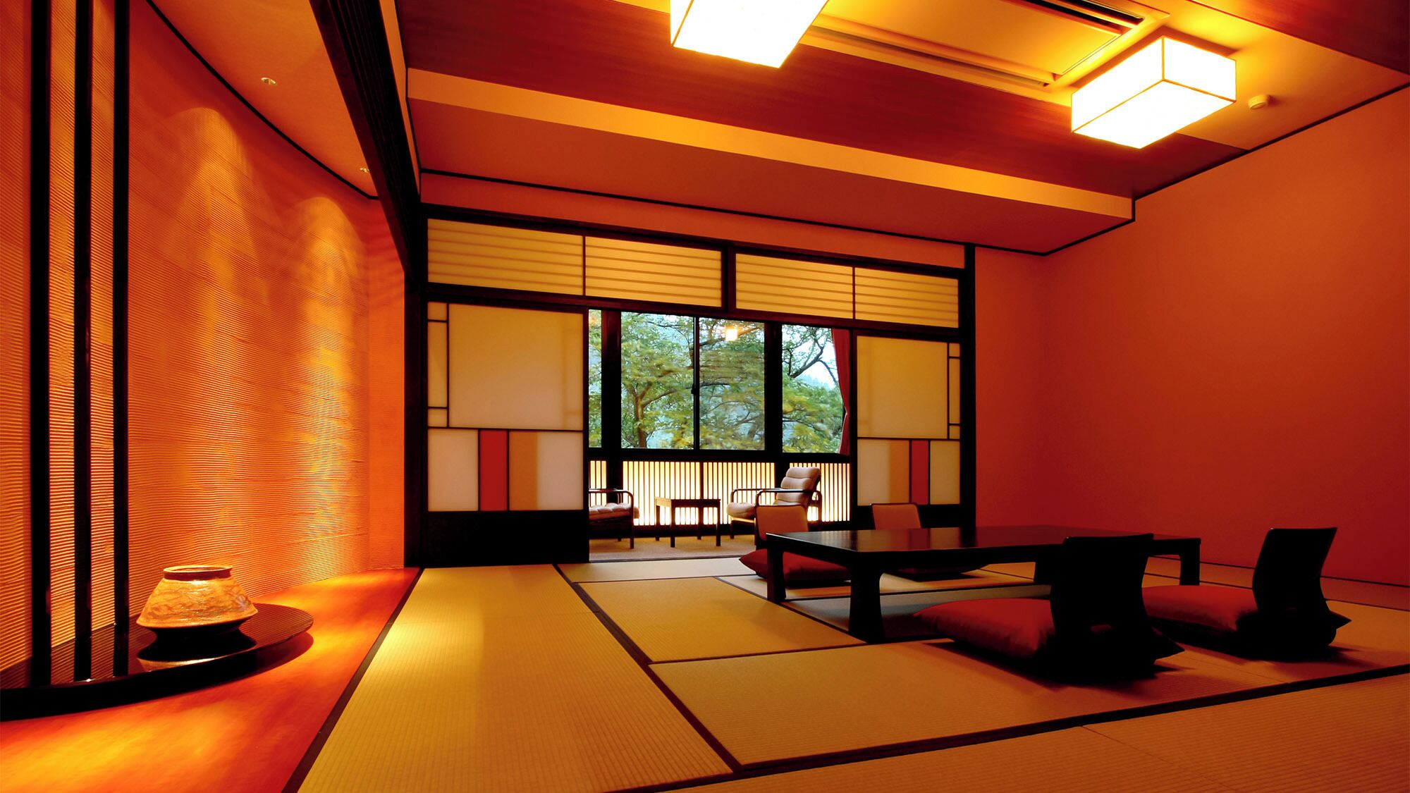 Una habitación japonesa tradicional con suelo de tatami, puertas correderas shoji y vista a árboles.