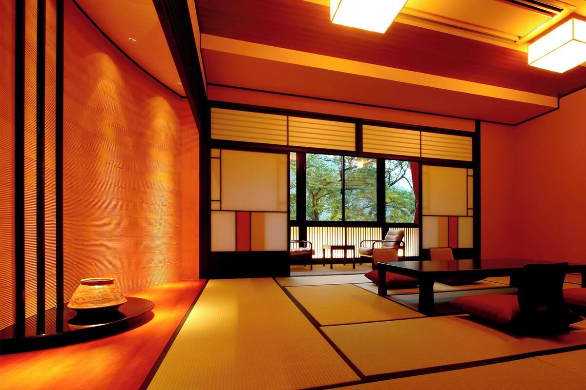 Ein traditioneller japanischer Raum mit Tatami-Böden, gleitenden Shoji-Schiebetüren und Blick auf Bäume.