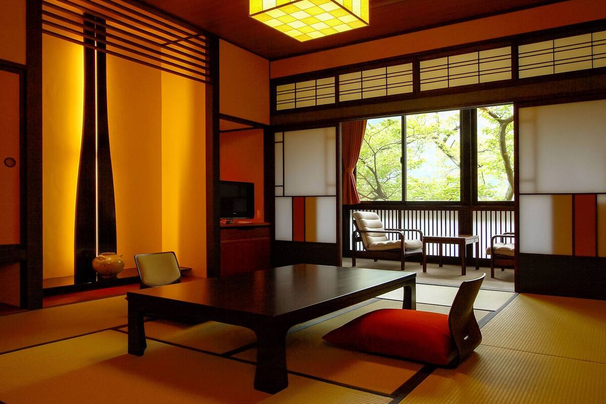 Ein traditioneller japanischer Raum mit Tatami-Bodenbelag, einem niedrigen Tisch und verschiebbaren Türen.