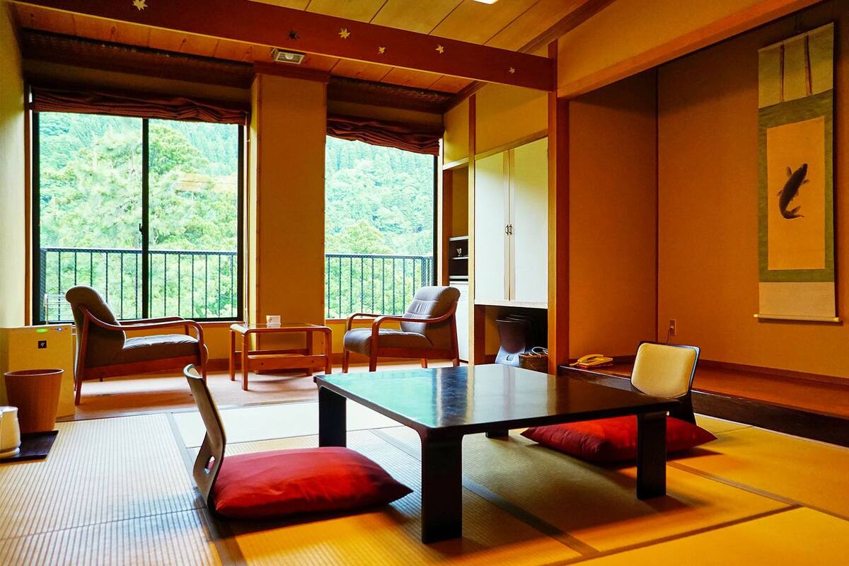 Ein traditioneller japanischer Raum mit Tatami-Böden, einem niedrigen Tisch und Stühlen.
