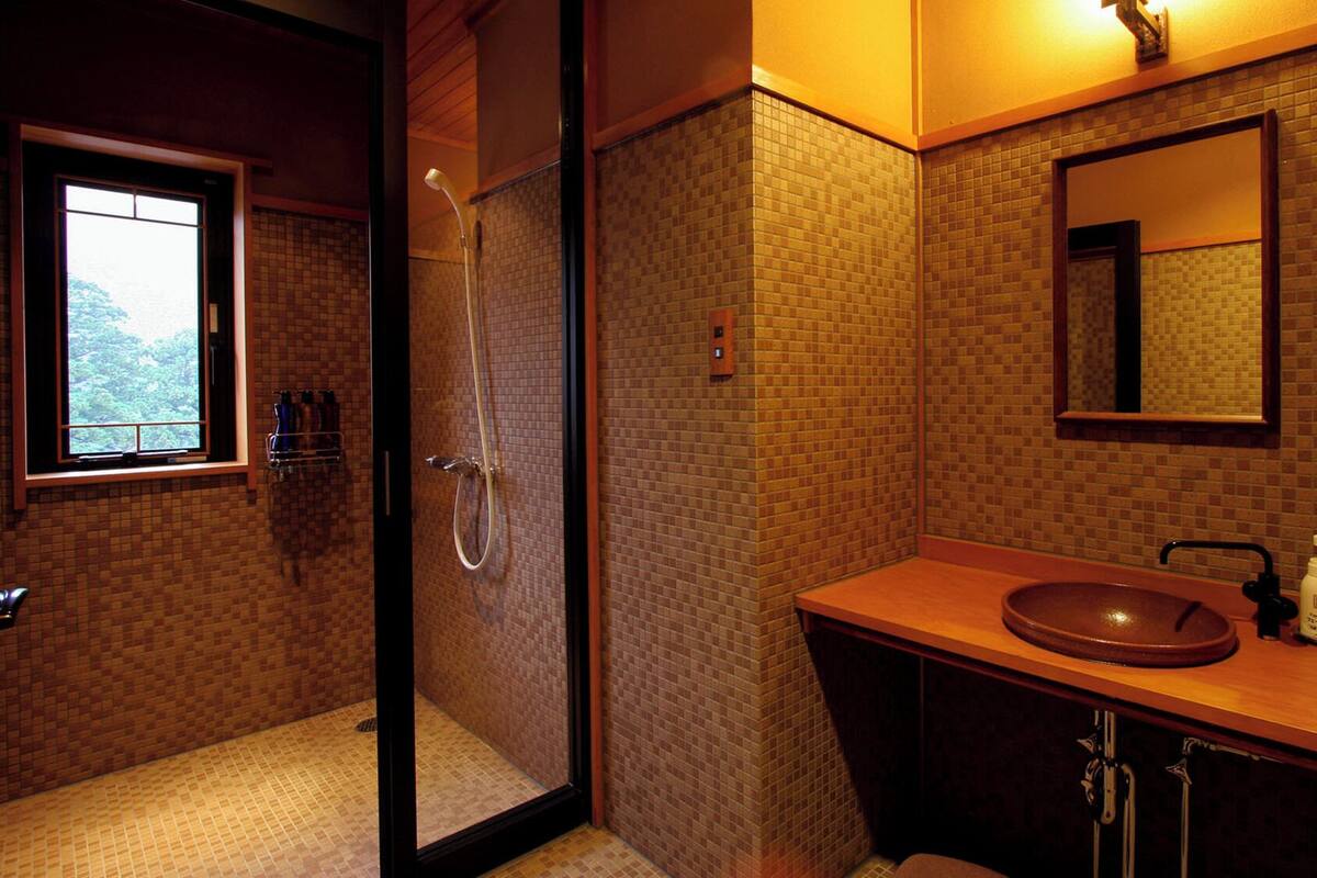 Ein Badezimmer mit Dusche, Waschbecken, Spiegel und Fenster.