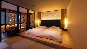 A traditional Japanese-style room with tatami flooring, a low platform bed, sliding doors with geometric patterns, and a headboard with a textured design.