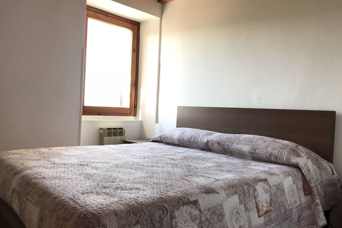 A bedroom with a bed, a window, and a radiator.