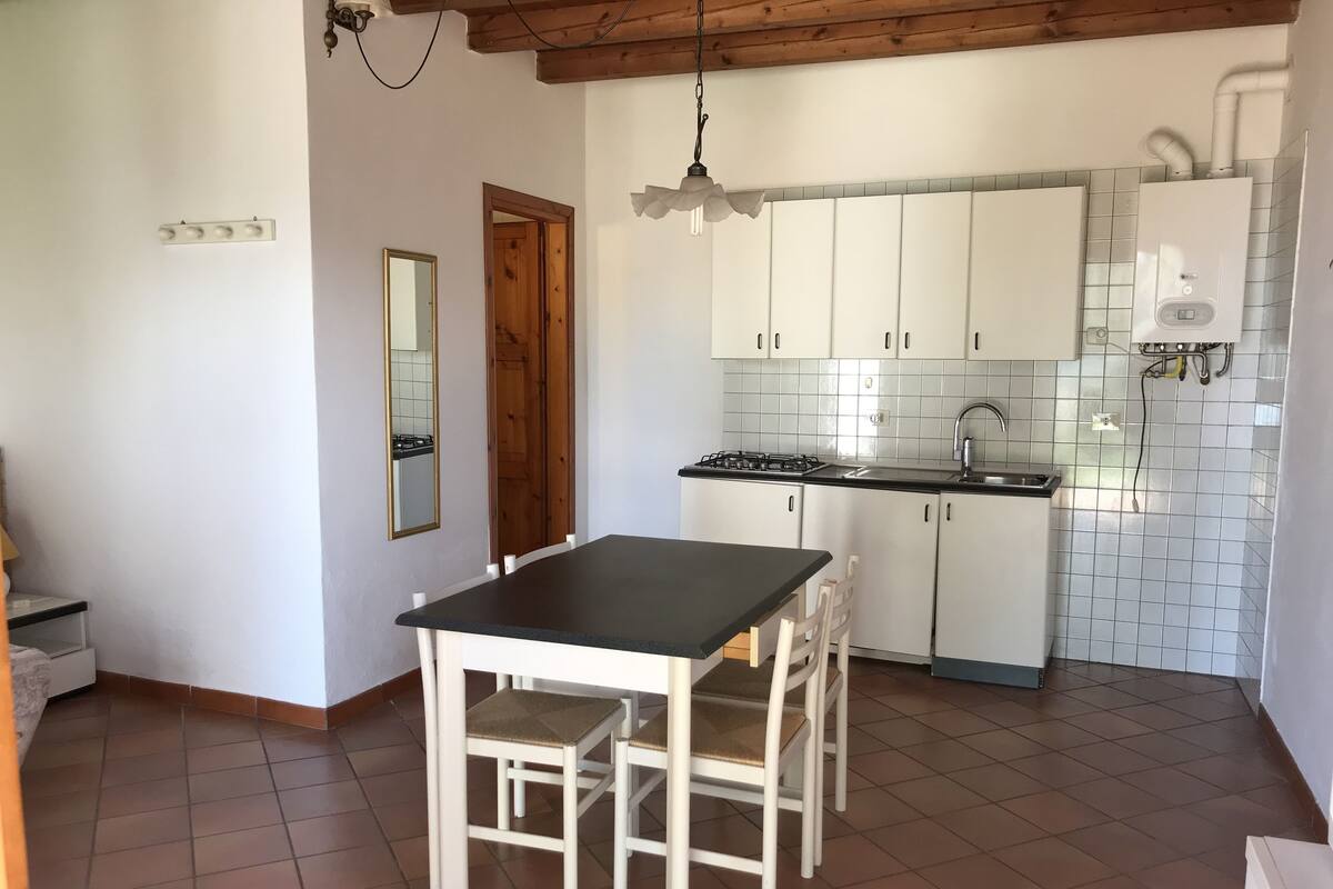 A kitchen with white cabinets, a black countertop, and a tiled backsplash.