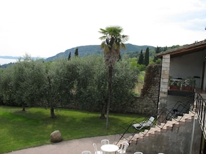 Un patio con mobiliario exterior, una escalera que conduce a un nivel superior y vistas de un paisaje montañoso.