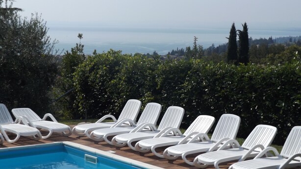 A pool area with white lounge chairs and a view of the sea. - Ca' Pignoi (Garda)