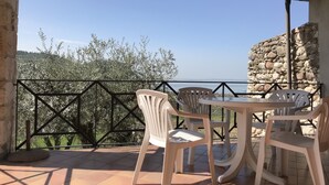A terrace with a table and chairs, a stone wall, and a view of the sea. - Ca' Pignoi (Garda)
