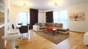 A modern living room with a sofa, coffee table, and dining area. - Sarap apartments Budva (Budva)