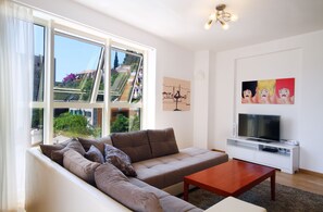 Departamento de lujo, 2 habitaciones, vista al mar | Área de sala de estar | Televisión de pantalla plana de 32 pulgadas con canales por cable