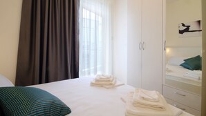 A hotel room with a bed, a wardrobe, and a window with curtains. - Sarap apartments Budva (Budva)