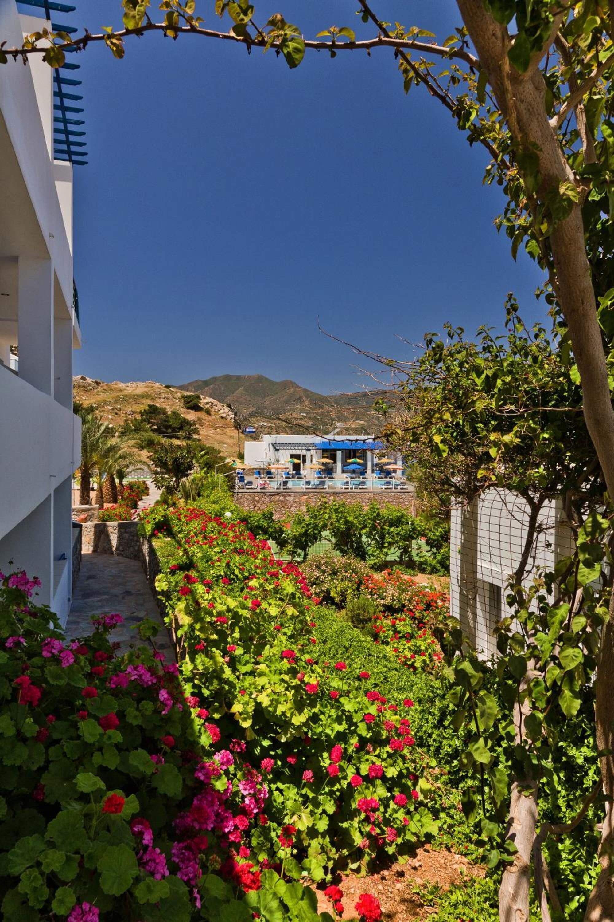 A hotel with a pool area, surrounded by lush gardens and a mountainous backdrop.