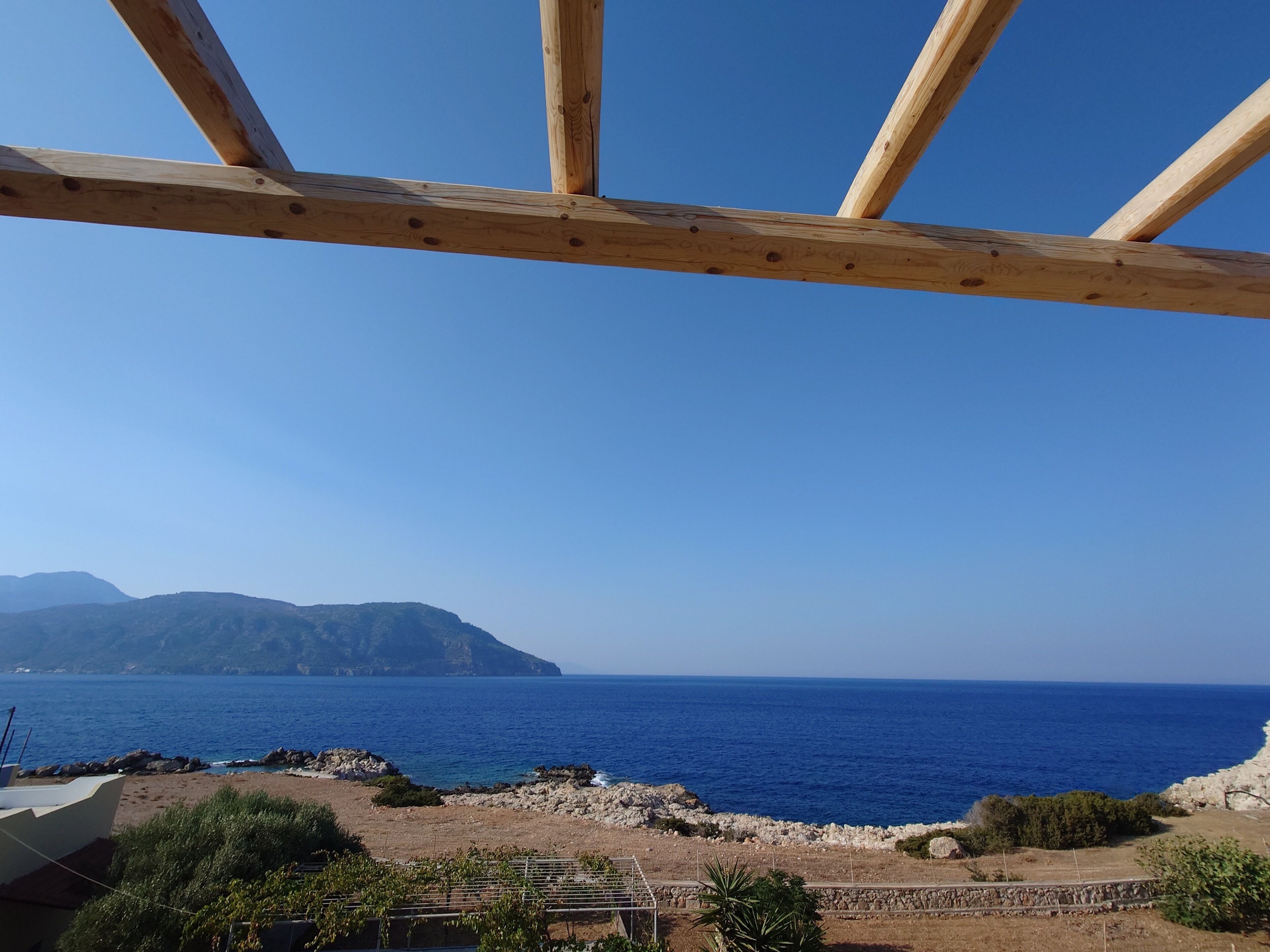 Una estructura de madera con vista al mar y una montaña distante.