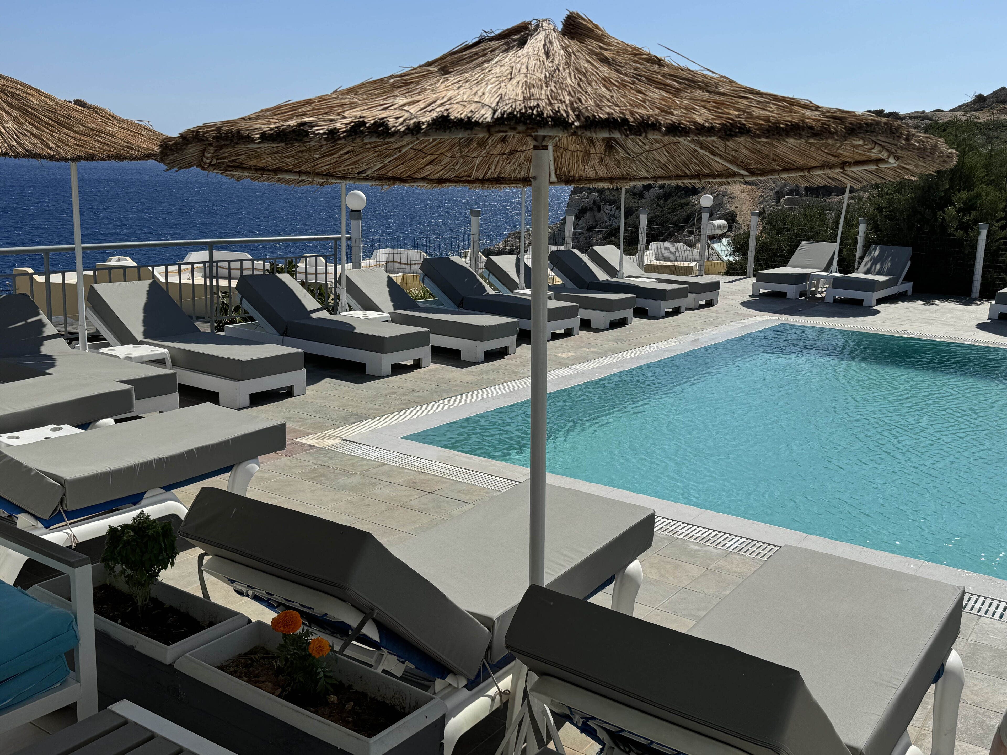 A poolside area with lounge chairs and umbrellas, overlooking a body of water.
