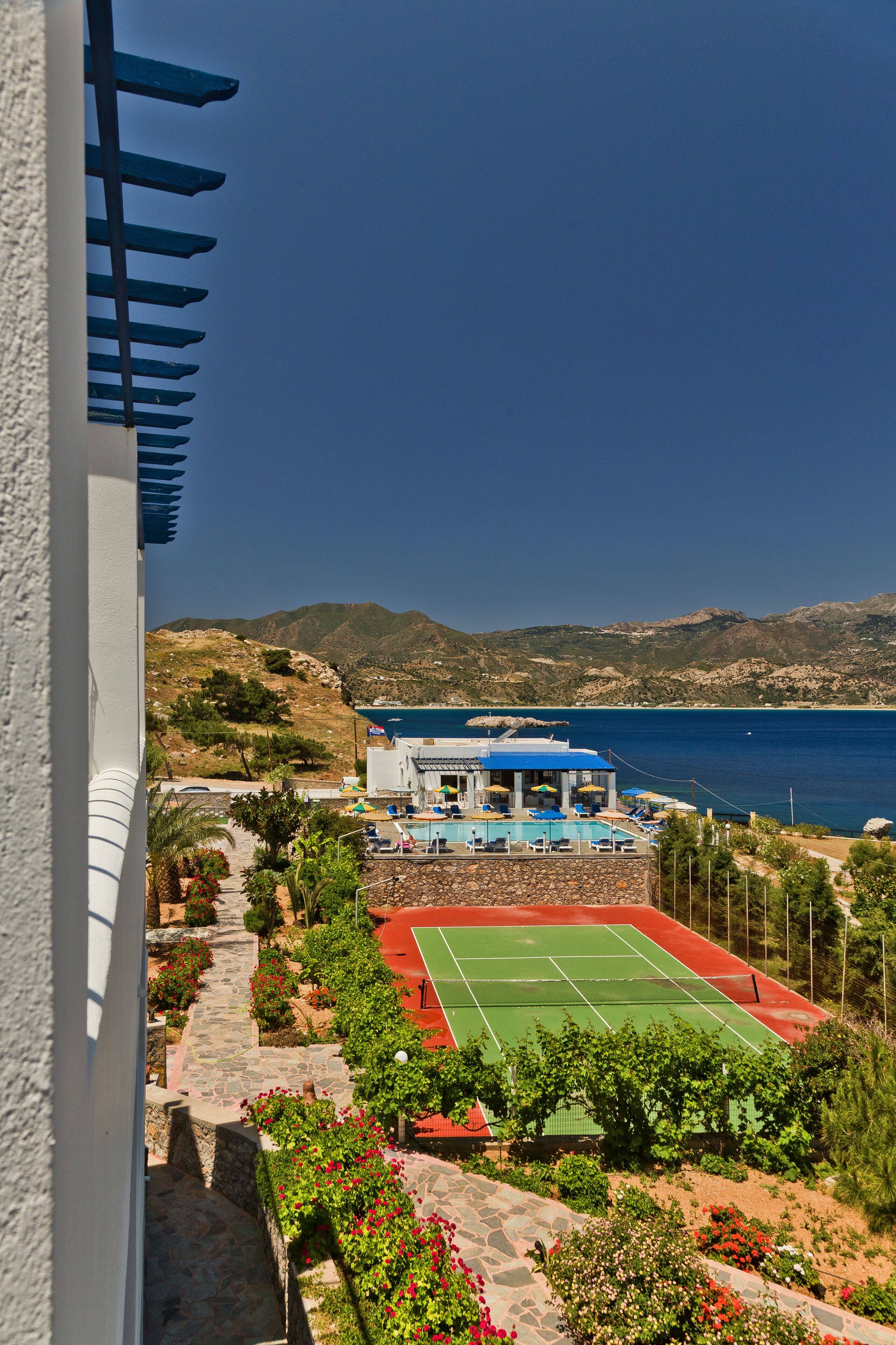 Un hotel con cancha de tenis, piscina y vistas panorámicas a la montaña.
