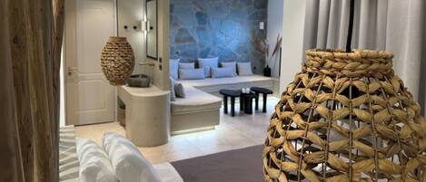 A modern living room with a stone wall, a sofa, a coffee table, and a wicker lamp.