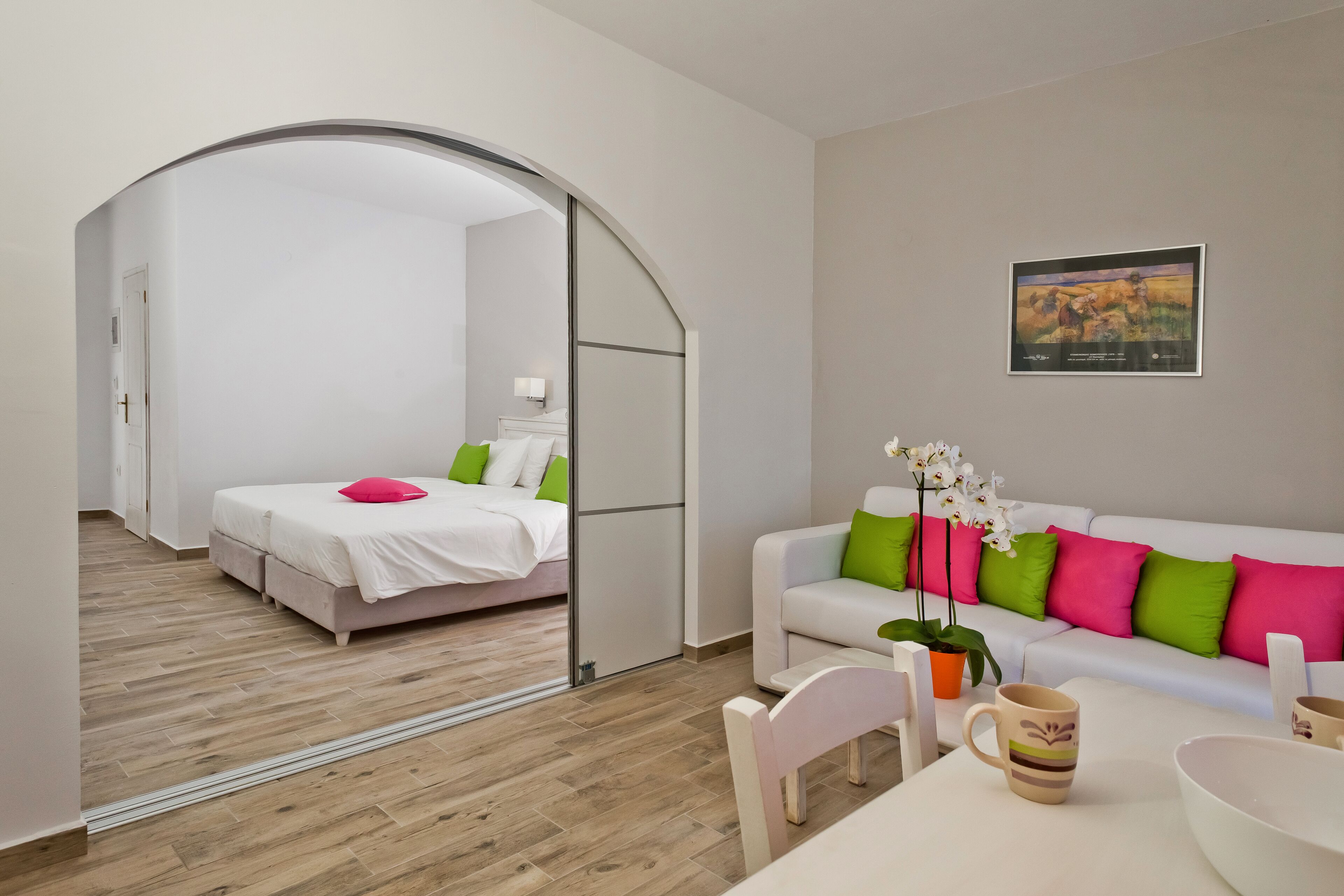 Una habitación de hotel moderna con una cama, un sofá, una mesa de comedor y una pequeña cocina.