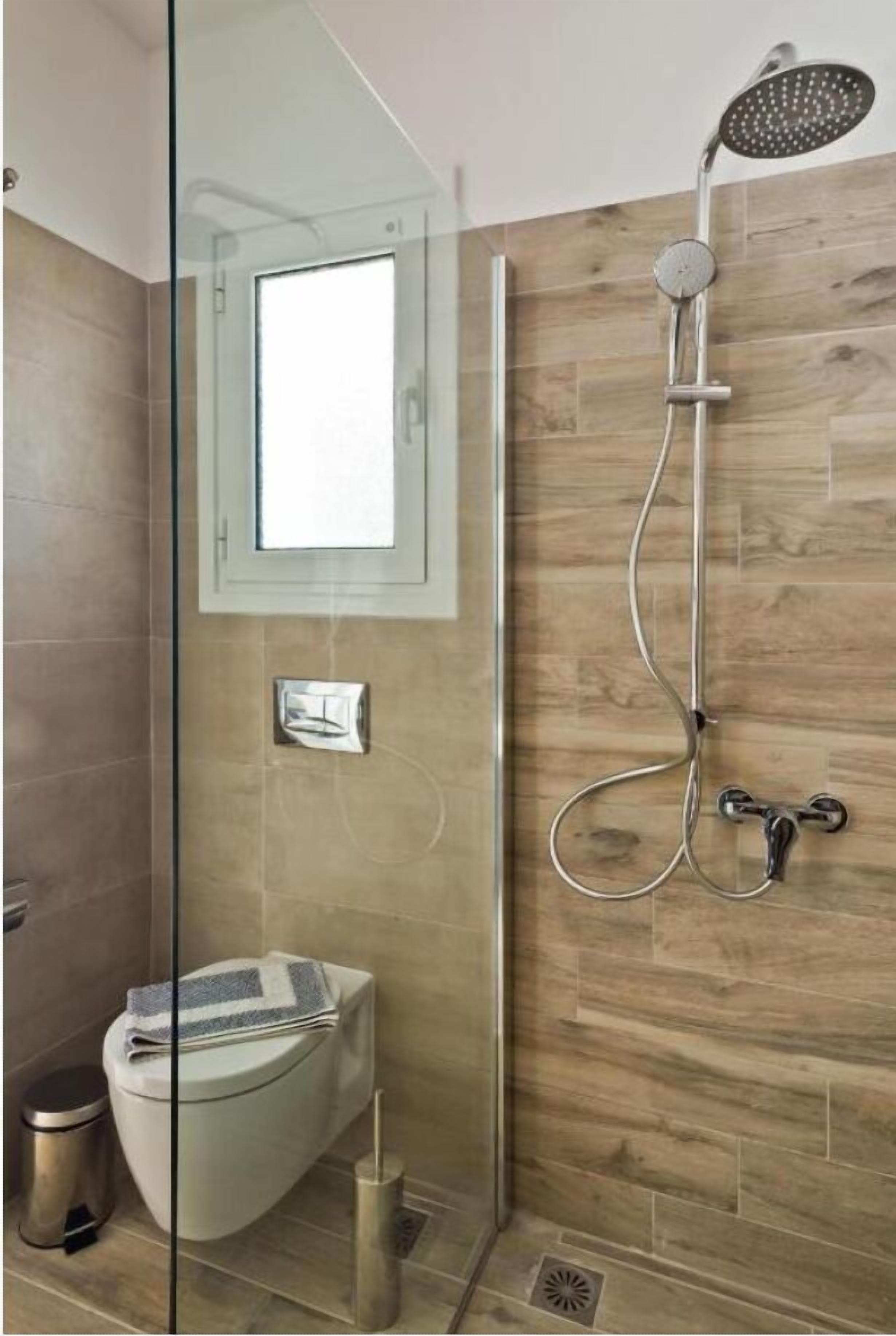 A modern bathroom with a glass-enclosed shower, a toilet, and a bidet.