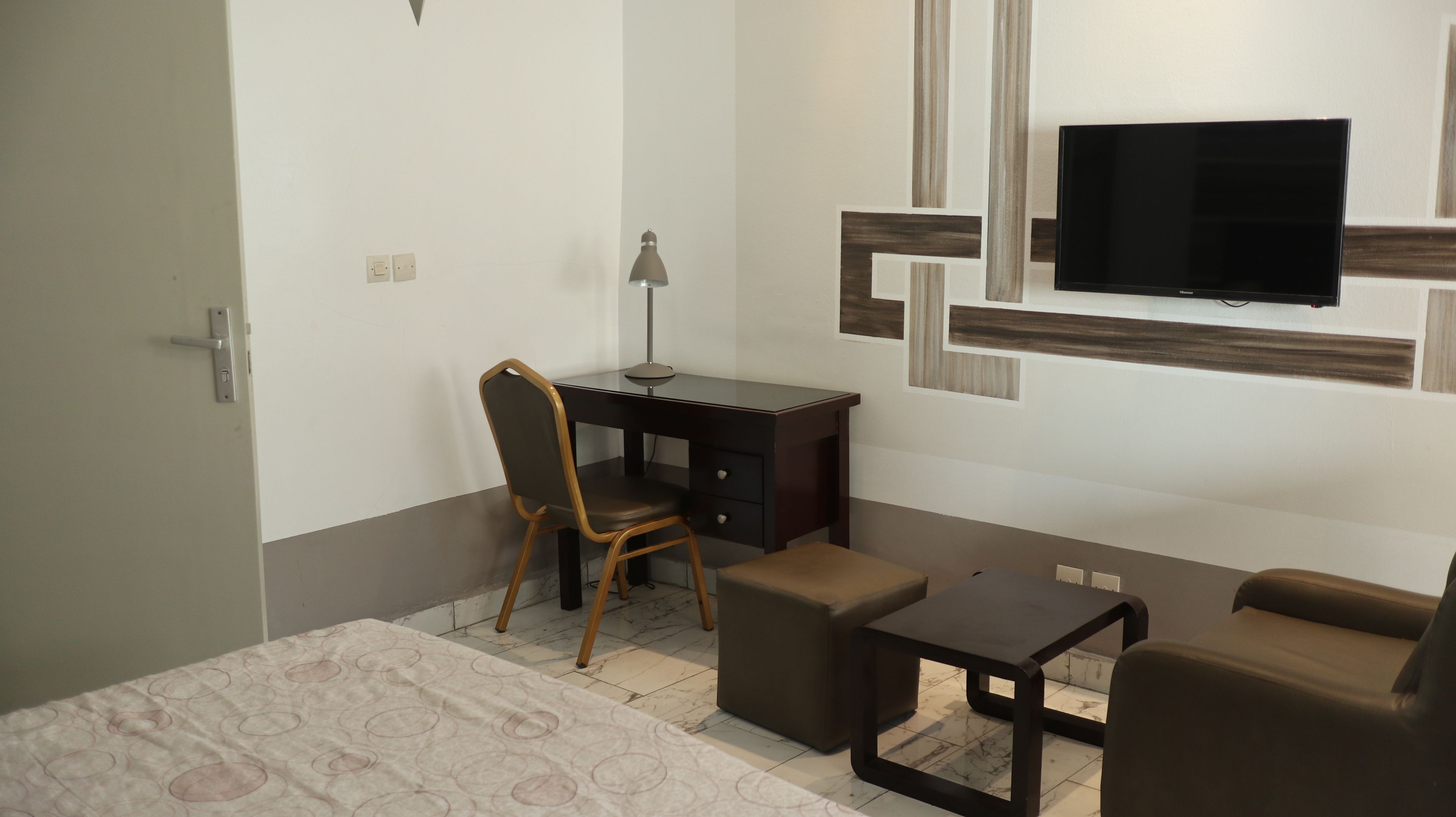 A modern hotel room with a desk, chair, and a television mounted on the wall.