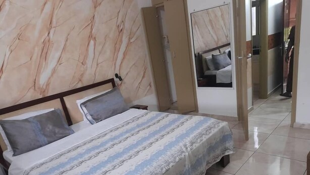 A hotel room with a bed, a nightstand, a mirror, and a wardrobe.