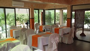 A restaurant with tables set for dining, large windows, and an air conditioning unit.
