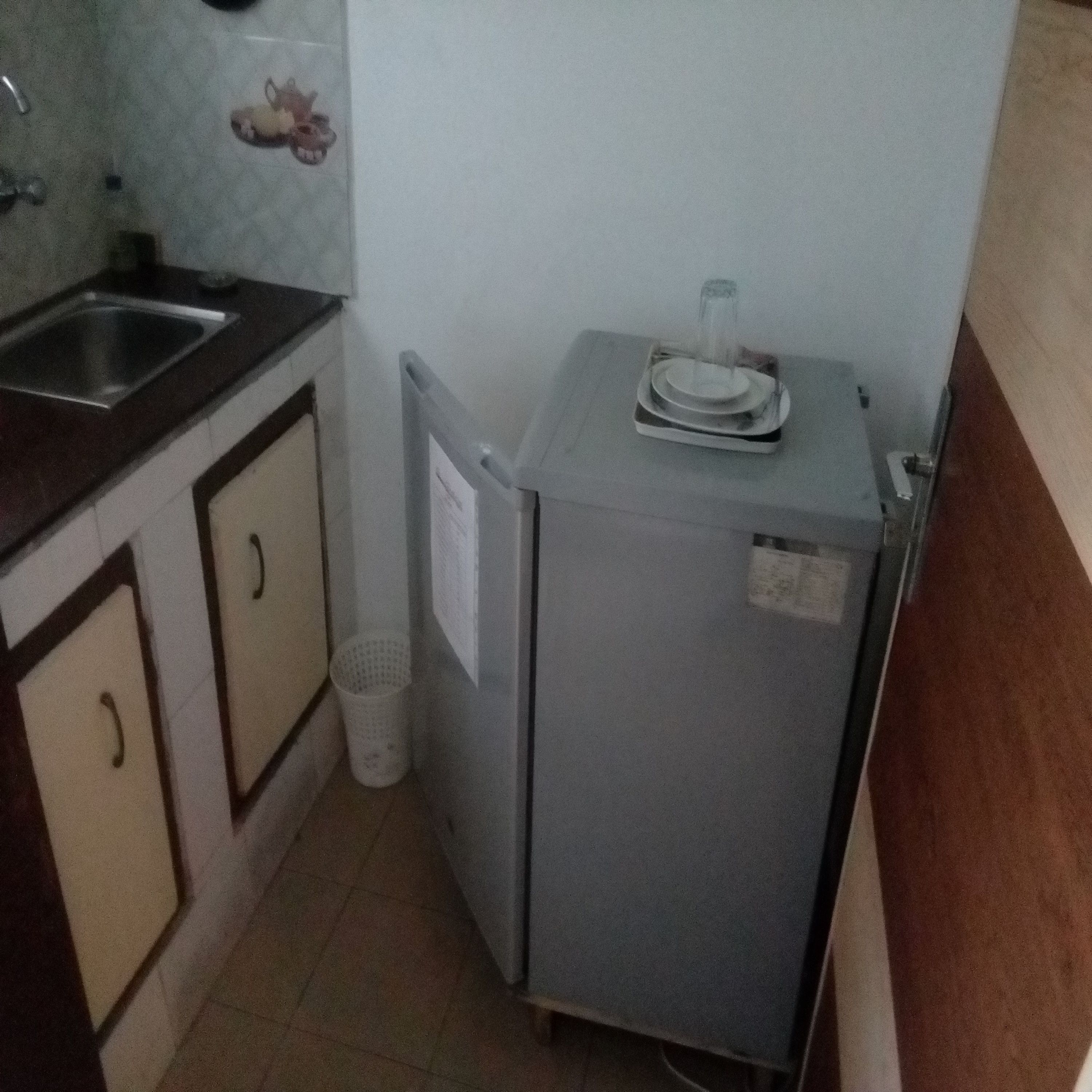 A compact kitchen with a sink, cabinets, and a small refrigerator.