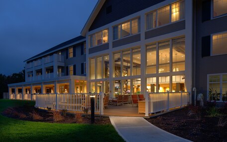 A multi-story hotel with a covered outdoor seating area and large windows.