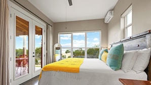 A bedroom with a large bed, a view through the glass doors, and a dining area visible outside. - Hill Country Casitas (Dripping Springs)