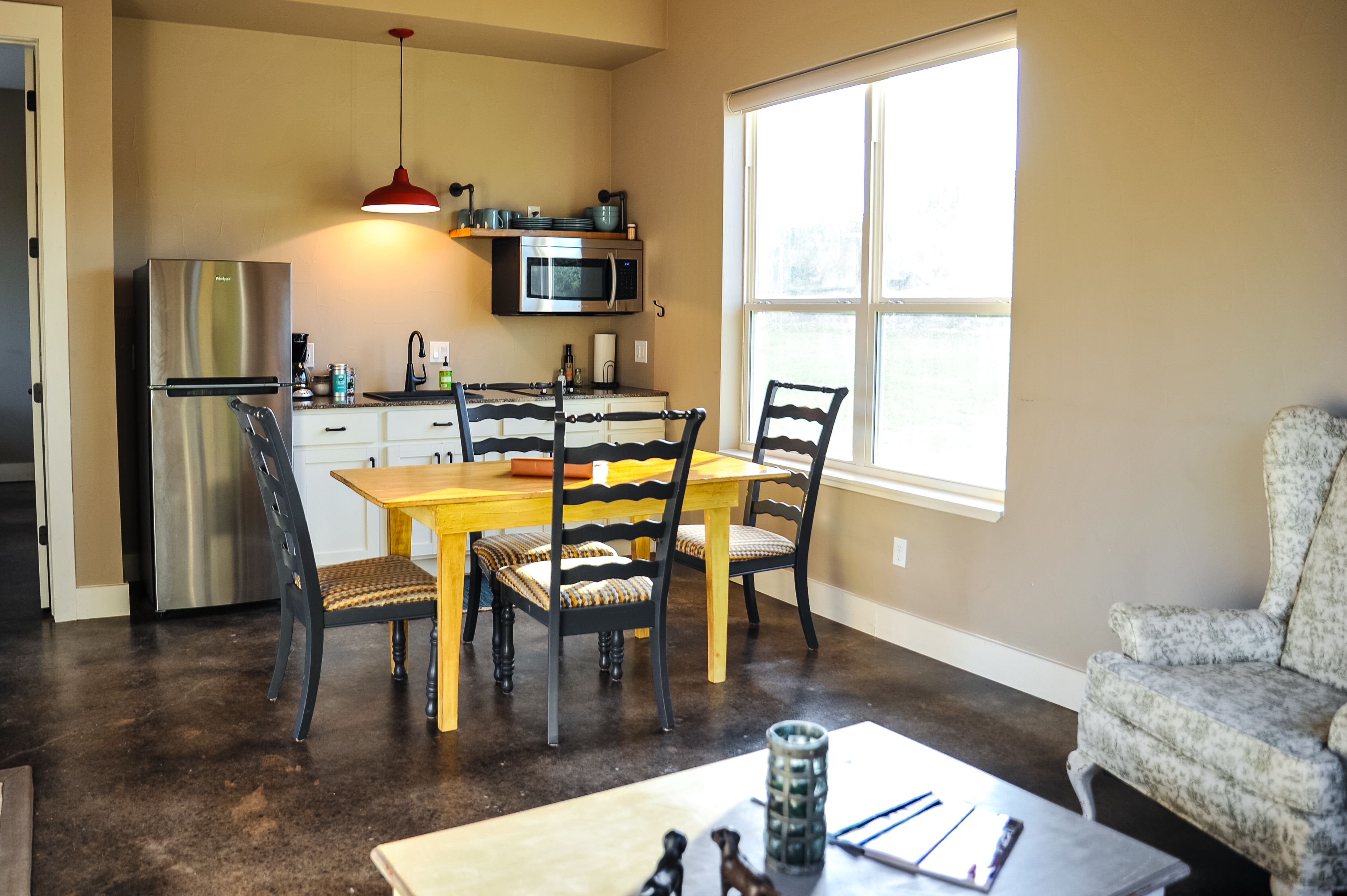 Una cocina moderna con un refrigerador de acero inoxidable, un microondas y un comedor con mesa y sillas de madera.