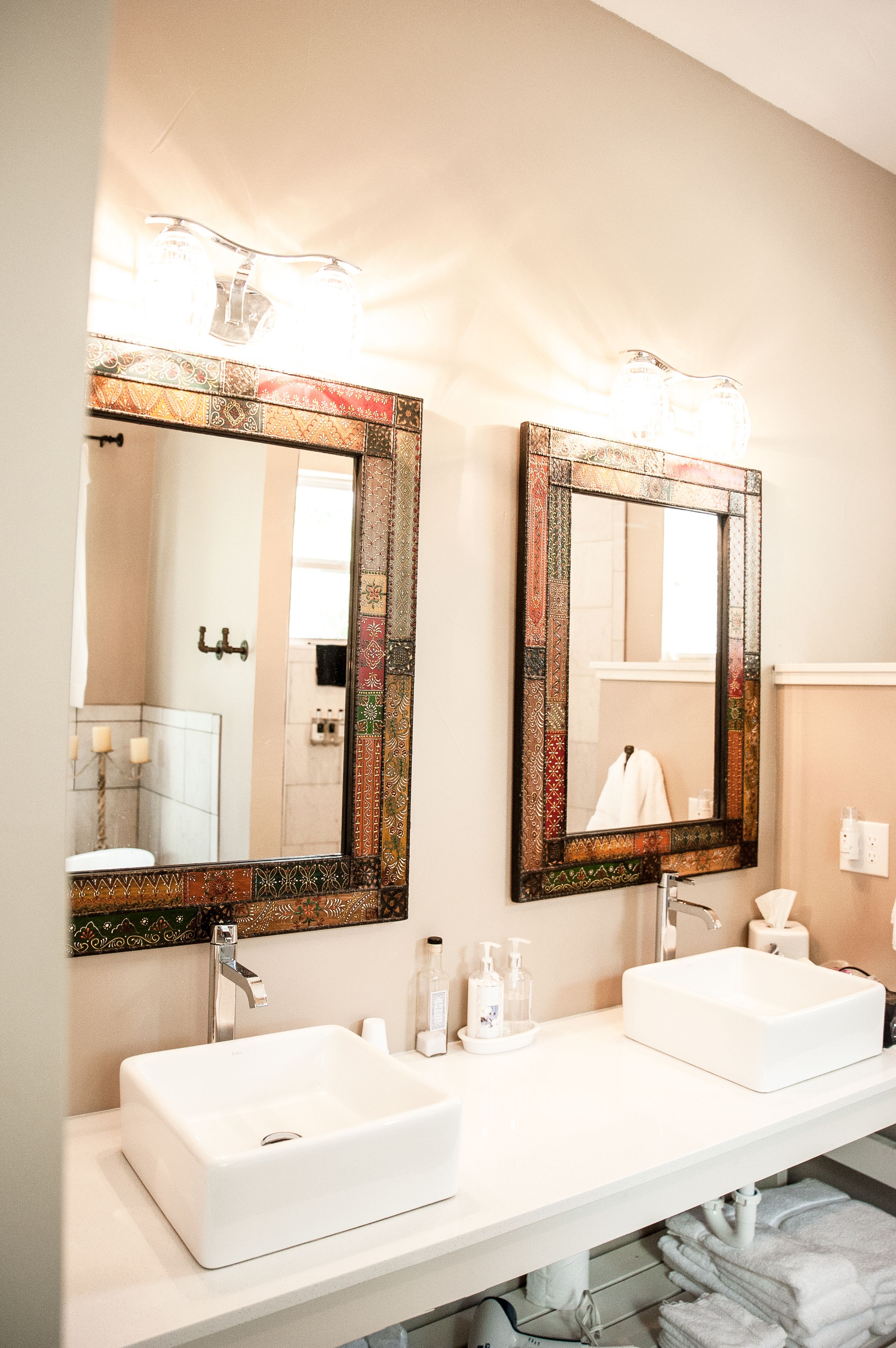 A bathroom with two white sinks, a large mirror with a decorative frame, and a towel rack with folded towels.